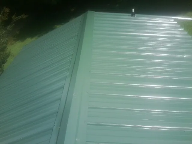 New green metal panels meeting at the ridge of a roof — Flat Roof Repair work by our crew in Terry