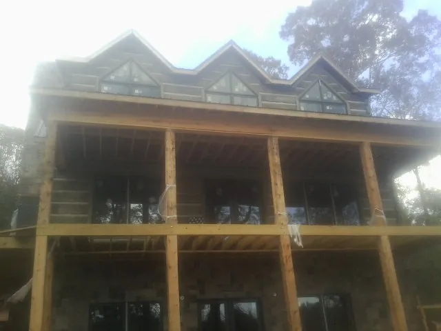 Dormers and porch framing on a large log home under construction — Roof Coating work by our crew in Terry