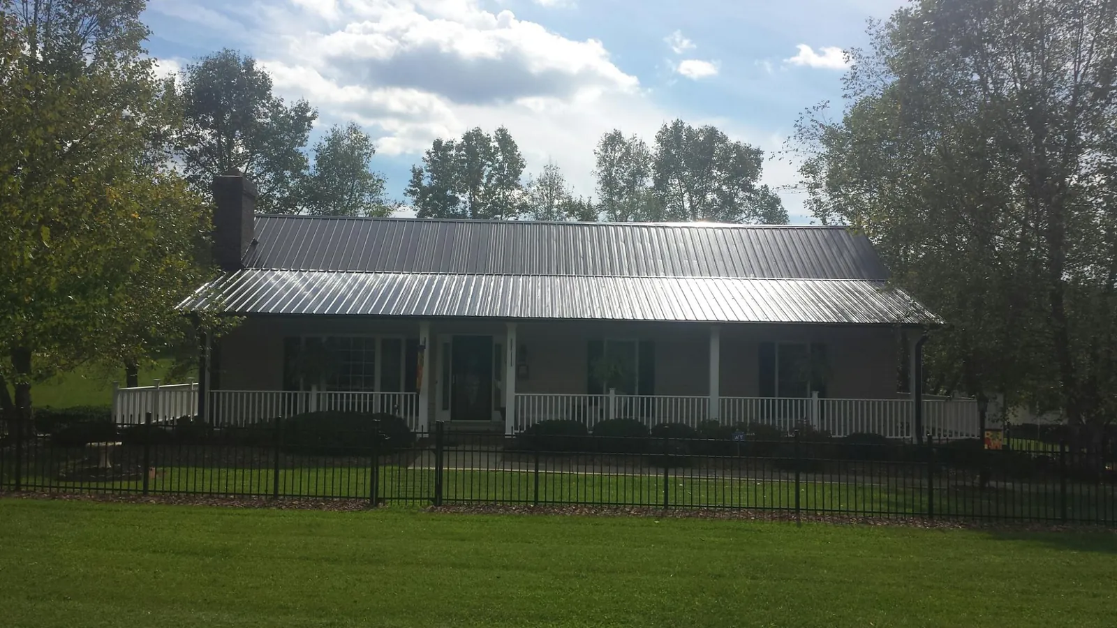 Gray metal roof on a brick ranch with a full width front porch — Gutter Guard Installation work by our crew in Terry