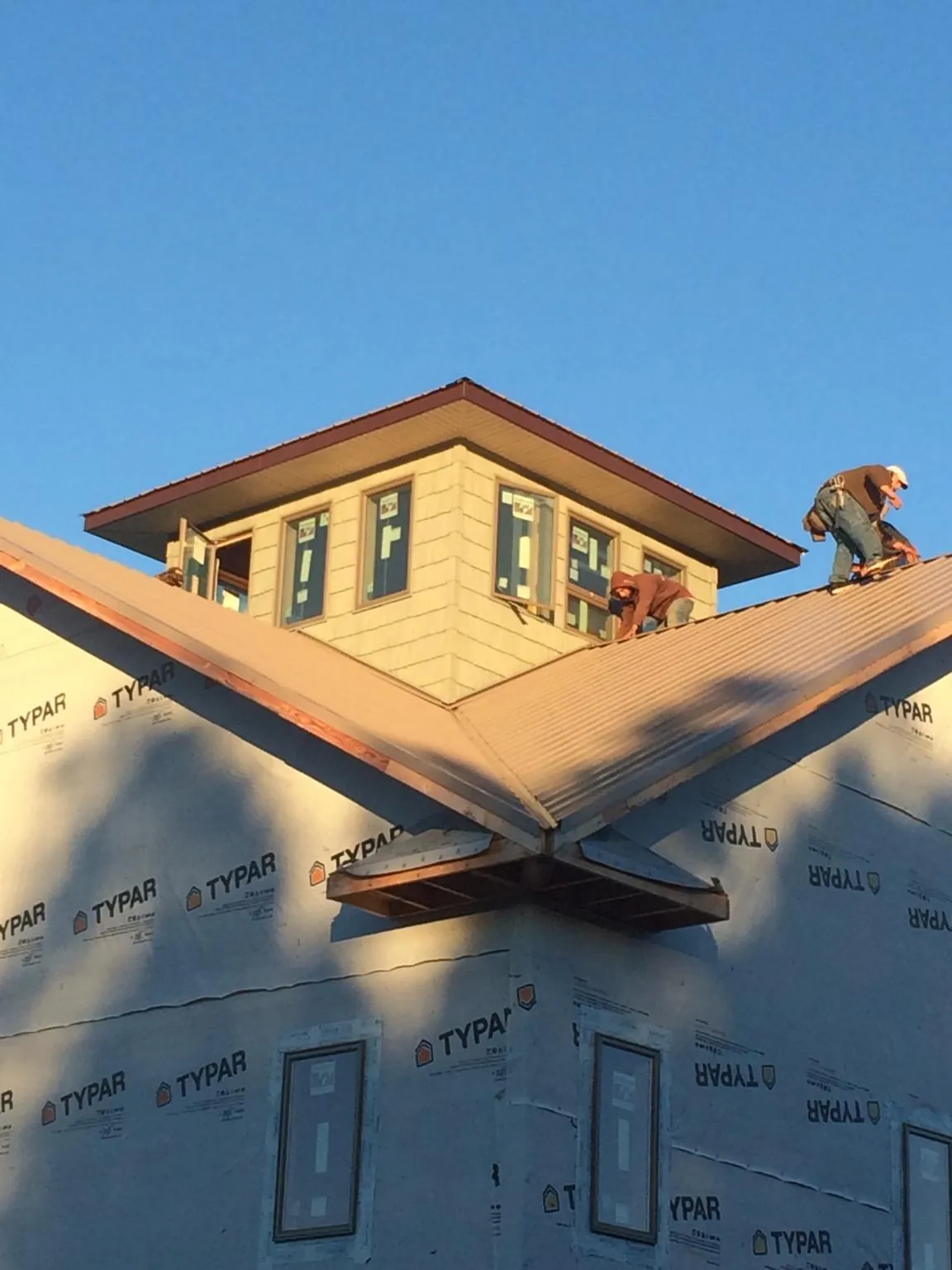 Roofers working around a rooftop cupola on a new metal roof at sunset — Roof Waterproofing in Terry by Roofing Brothers